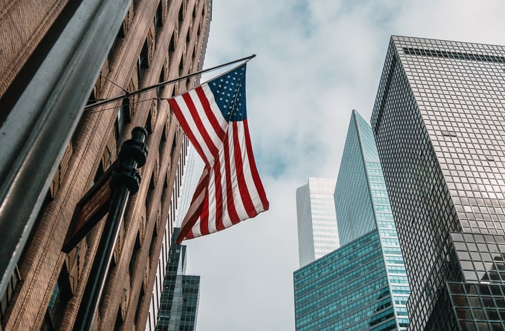 usa-united-states-america-flag-flagpole-near-skyscrapers-cloudy-sky